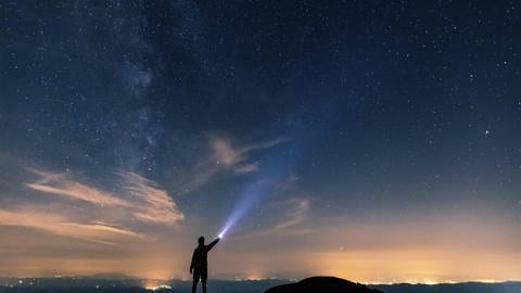 Ein Mensch leuchtet mit einer Taschenlampe gen Sternenhimmel (Foto: IMAGO, William Perugini via www.imago-images.de)