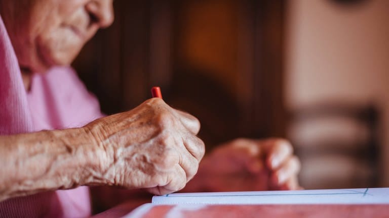 Nahaufnahme der Hand einer älteren Frau beim Zeichnen