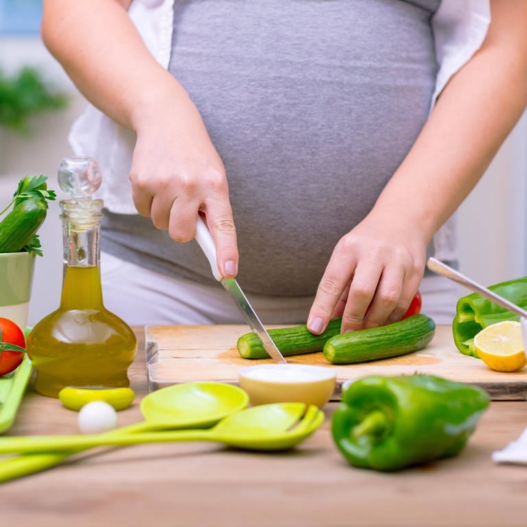 Eine Schwangere bei der Zubereitung von Essen (Foto: IMAGO, imago images / Panthermedia)