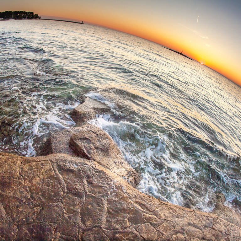 Sonnenuntergang, Meer und Strand mit einem Fischaugen-Objektiv aufgenommen in Porec, Kroatien 