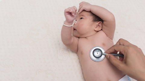 Ein Baby wird mit einem Stethoskop abgetastet. (Foto: IMAGO, IMAGO / agefotostock)