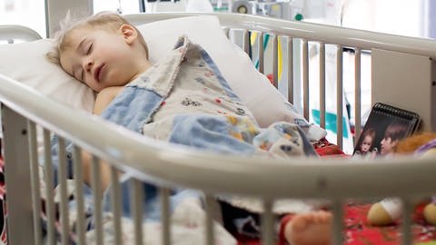 Ein Kleinkind schläft im Krankenhausbett. (Foto: IMAGO, IMAGO / Cavan Images)
