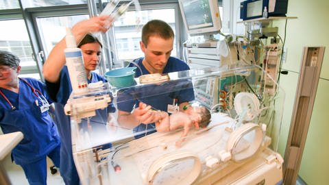 Kinderkrankenpfleger künmmern sich um ein Baby. (Foto: IMAGO, IMAGO / C3 Pictures)