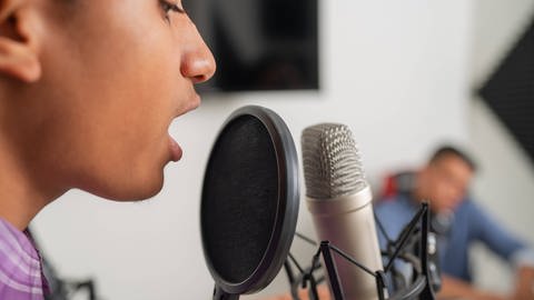 Ein Mann singt in einem Tonstudio (Foto: IMAGO, IMAGO / Addictive Stock)