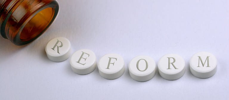 Pillen mit der Aufschrift "Reform" sind aneinandergereiht. (Foto: dpa Bildfunk, CHROMORANGE / Bilderbox)