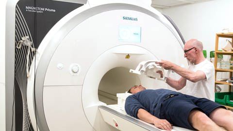 Arzt legt Patienten eine Kopfspule an einem Magnetresonanztomograph (MRT) an. (Foto: picture-alliance / Reportdienste, /dpa)