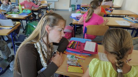 Frau hilft Kind in der Schule (Foto: picture-alliance / Reportdienste, picture alliance/spa I Bernd Settnik)