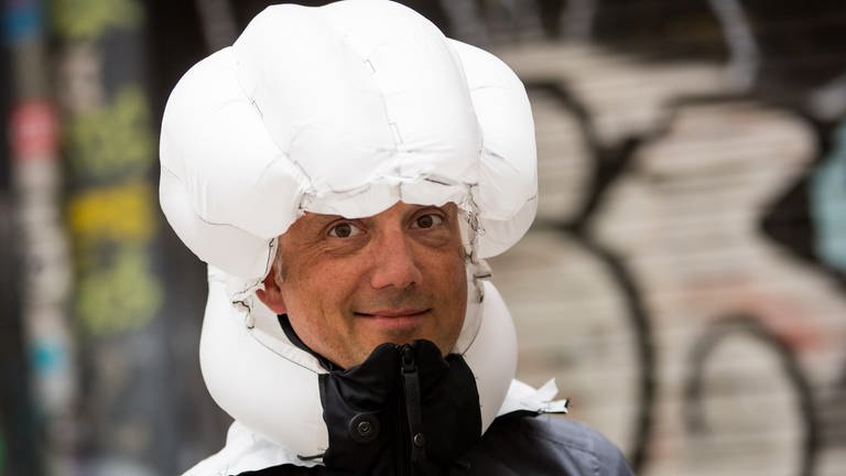Jens Meer, Generalimporteur des schwedischen "Hövding", demonstriert bei einem Medientermin die Funktionsweise des "Airbag für Radfahrer". (Foto: IMAGO, dpa Bildfunk, picture alliance/dpa | Christian Charisius)