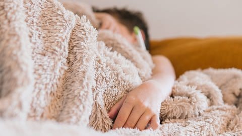 Kind liegt krank im Bett. (Foto: IMAGO, Addictive Stock)