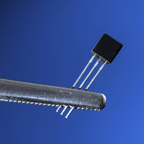 Ein elektronischer Transistor wird von einer Pinzette gehalten. (Foto: IMAGO, IMAGO / Science Photo Library)