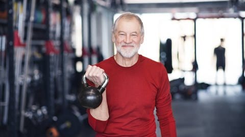 Älterer Mann beim Training mit der Kettlebell im Fitnessstudio. (Foto: IMAGO, IMAGO / Westend61)