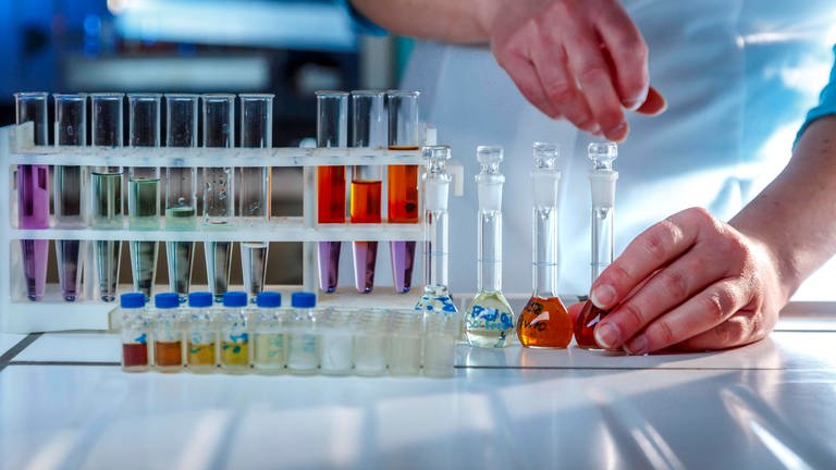 Das Bild zeigt verschiedenfarbig gefüllte Reagenzgläser in einem Labor. (Foto: IMAGO, Rainer Weisflog)