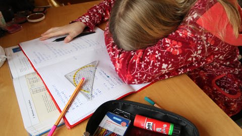 Kind sitzt vor Schulaufgaben und versenkt den Kopf in der Armbeuge. (Foto: picture-alliance / Reportdienste, picture alliance/dpa | Philipp Brandstädter)