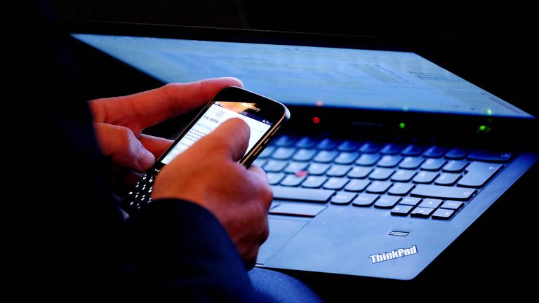 Person sitzt am Laptop und am Smartphone gleichzeitig (Foto: picture-alliance / Reportdienste, / dpa)