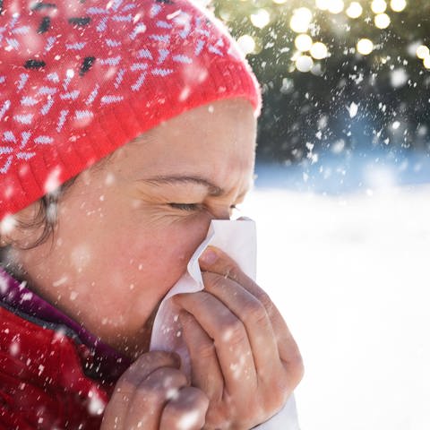Eine Frau putzt sich die Nase im Schnee. (Foto: IMAGO, IMAGO / Panthermedia)