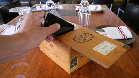Gast in Restaurant legt sein Handy weg, um während des Essens auf sein Handy zu verzichten. (Foto: picture-alliance / Reportdienste, picture alliance/dpa | Johannes Schmitt-Tegge)