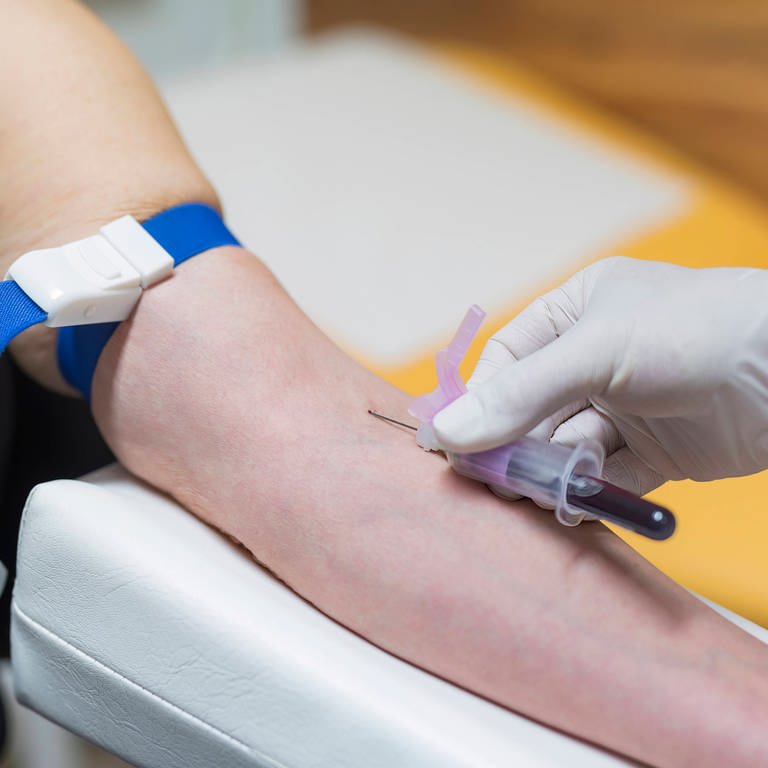 Ein Arzt entnimmt eine Blutprobe von einer Frau. (Foto: IMAGO, IMAGO / Zoonar)