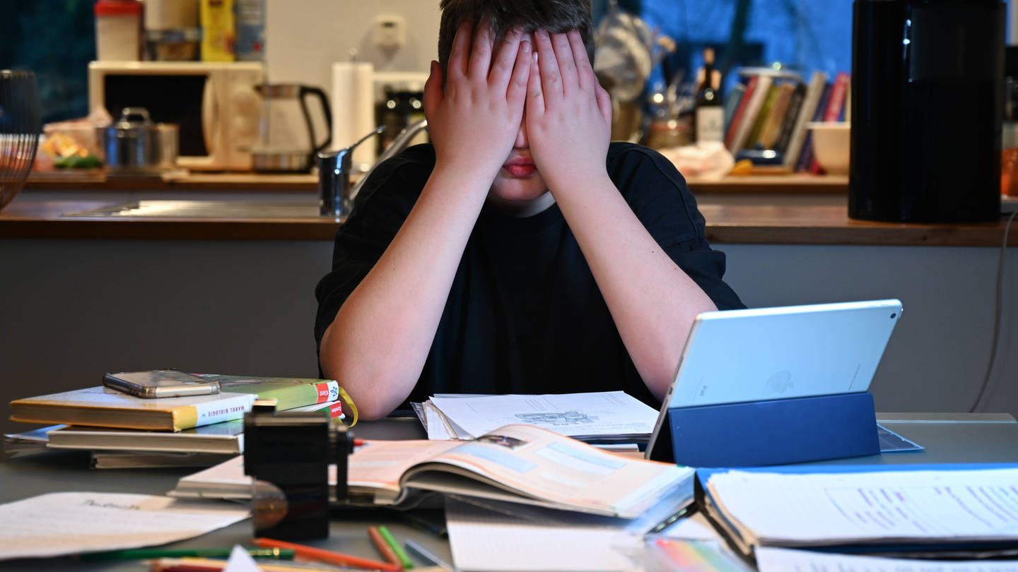 Das Bild zeigt einen verzweifelten Schüler über seinen Lernaufgaben. (Foto: IMAGO, Petra Schneider)