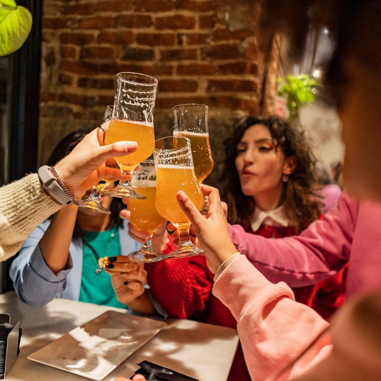 Freunde stoßen mit ihren alkoholischen Getränken in einer Bar an. (Foto: IMAGO, IMAGO / Westend61)