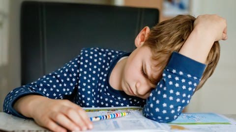 Unglücklicher Junge hat den Kopf auf dem Tisch neben seinem Schulheft abgelegt, tags: Schulschließungen, gelernt, Pandemie (Foto: IMAGO, Pond5 Images)