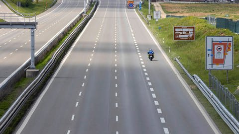 Ein Motorrad fährt einsam auf einer vierspurigen Autobahn. (Foto: IMAGO, imago images/Arnulf Hettrich)