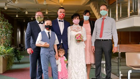 Brautpaar und wenige Gäste mit Mundschutz (Foto: IMAGO, imago images / MiS)