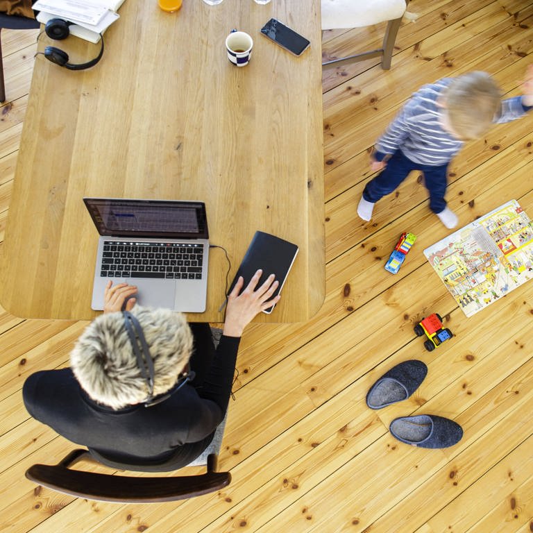 Frau sitzt am Laptop im Home Office und ihr Sohn springt herum (Foto: IMAGO, imago images/photothek)