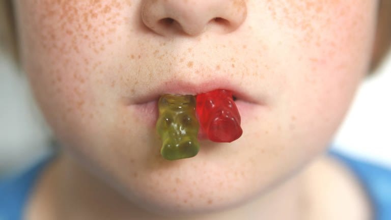 Gummibärchen kleben an einem Kindermund (Foto: IMAGO, imago images/Waldmüller)