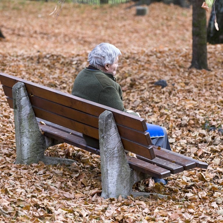 Senior sitzt auf einer Bank im Park