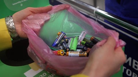 Nahaufnahme zweier Hände, die eine Tüte voller Batterien vor einem Sammelcontainer aus Karton offen halten. (Foto: IMAGO, IMAGO / Ukrinform)