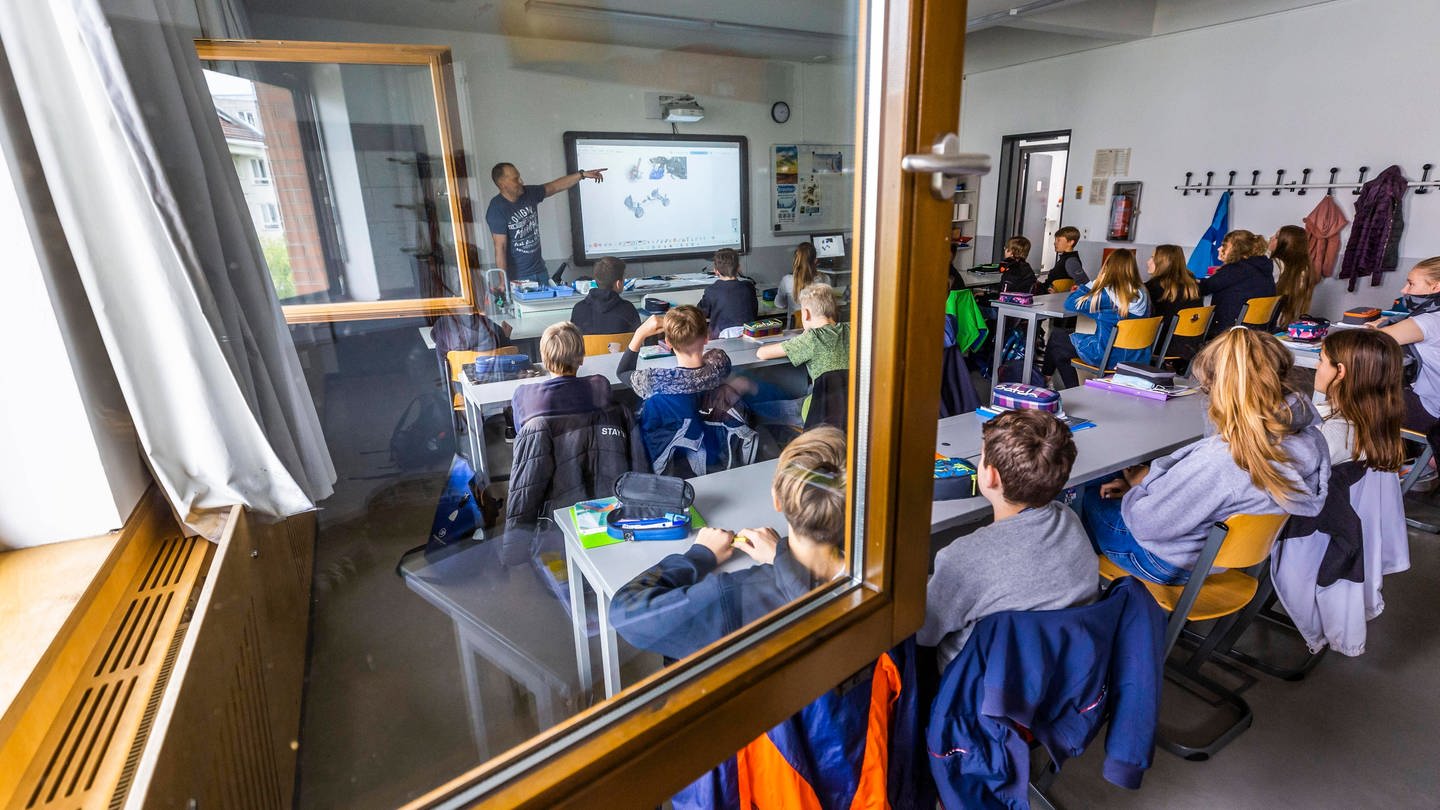 Schüler*innen sitzen in einem Klassenzimmer bei geöffnetem Fenster (Foto: IMAGO, IMAGO / imagebroker)
