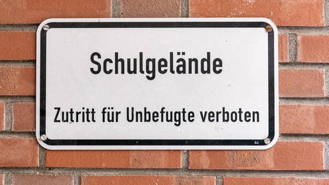 Ein Schild mit der Aufschrift "Schulgelände – Zutritt für Unbefugte verboten" auf einer Backsteinwand (Foto: IMAGO, IMAGO / Stefan Zeitz)