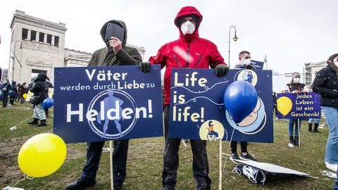 Zwei Demonstranten mit Schildern, darauf die Aufschriften: "Väter werden durch Liebe zu Helden" und "Life is life" - „Marsch fürs Leben“ am 20. März 2021 in München, die Schilder wurden vorgefertigt durch die Organisatoren ausgehändigt (Foto: IMAGO, IMAGO / ZUMA Wire)