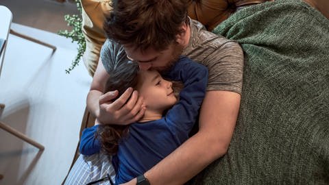 Vater umarmt kranke Tochter (Foto: IMAGO, Imago / Westend61)
