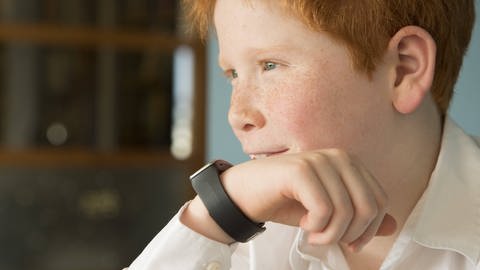 Ein Junge spricht in seine Smartwatch. (Foto: IMAGO, IMAGO / PhotoAlto)