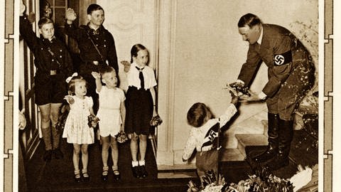 Sechs Kinder bei Hitlers 50. Geburtstag. Zwei der Jungen tragen die Uniform der Hitlerjugend. In der NS-Erziehung soll vor allem die Jugend von Grund auf geformt werden.