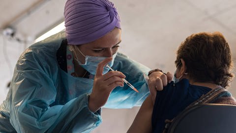 Eine Krankenschwester impft eine Person mit der vierten Auffrischungsdosis gegen Covid-19.