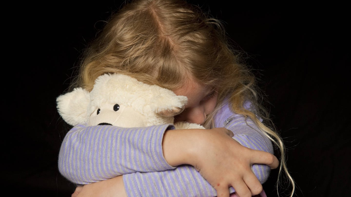 Mädchen kauert und hat einen Teddybären im Arm (Foto: IMAGO, IMAGO / imagebroker)