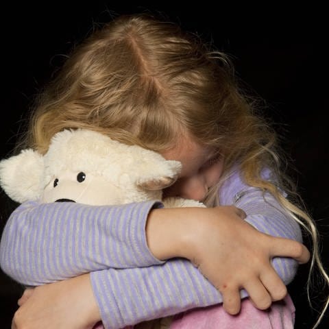Mädchen kauert und hat einen Teddybären im Arm (Foto: IMAGO, IMAGO / imagebroker)
