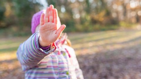 Junges Mädchen streckt ihre Hand als Stopp-Signal vor sich aus.
