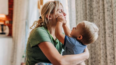 Erwünschte Berührungen haben einen positiven Einfluss auf die Gesundheit. Frau mit Kleinkind wird am Kopf berührt. (Foto: IMAGO, IMAGO/Westend61)