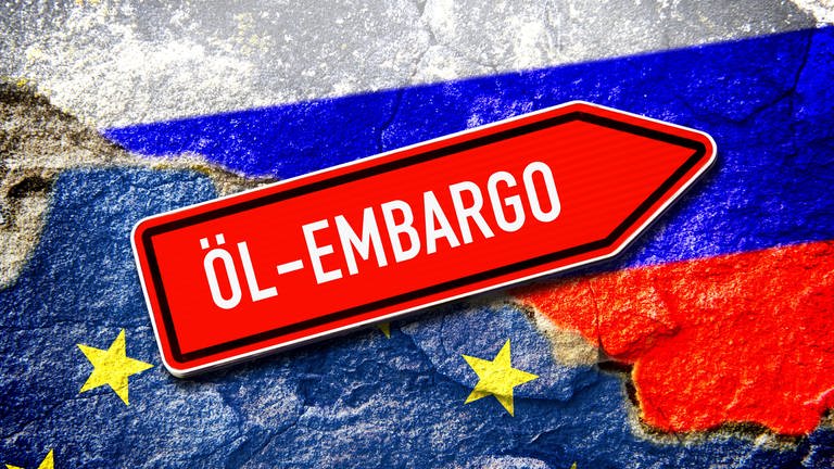 Schild mit der Aufschrift "Öl-Embargo" vor den Fahnen der EU und Russland. (Foto: IMAGO, IMAGO / Christian Ohde)