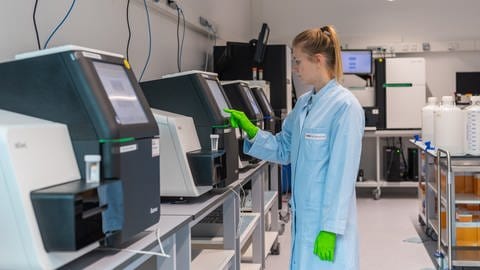 Eine Mitarbeiterin steht an einem DNA-Sequenziergerät. (Foto: picture-alliance / Reportdienste, dpa-Zentralbild)