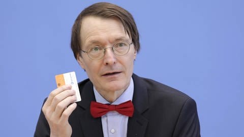 Karl Lauterbach hält bei einer Pressekonferenz einen Organspendeausweis in der Hand. (Foto: IMAGO, IMAGO / Jens Schicke)