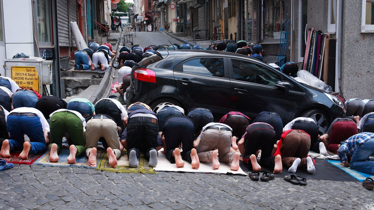 Muslime beim Gebet auf der Straße zwischen Autos (Foto: IMAGO, IMAGO / YAY Images)