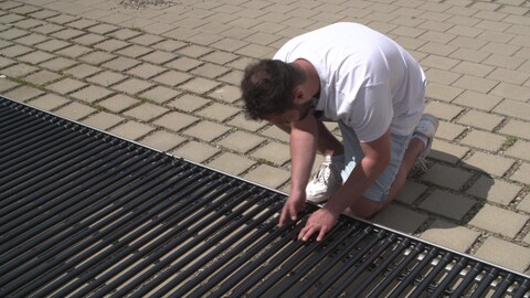 Ein Student arbeitet an der röhrenförmigen Solaranlage am Boden. Sie sieht aus wie eine große Heizung für Handtücher. (Foto: SWR)
