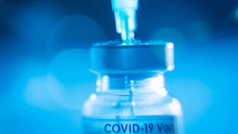 Eine Spritze wird aus einer Covid-19-Impfstoffampulle aufgezogen.