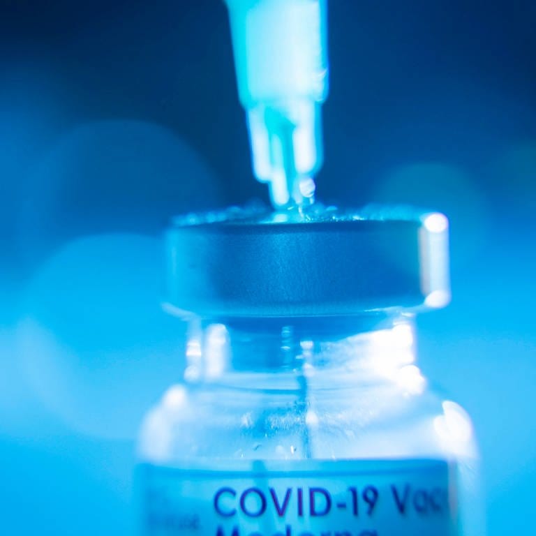 Eine Spritze wird aus einer Covid-19-Impfstoffampulle aufgezogen.