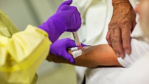 Eine Ärztin setzt eine Spritze mit Beruhigungsmittel am Arm eines Patienten an. (Foto: IMAGO, -)