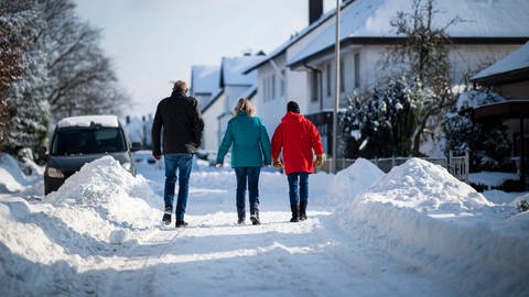 Ein Elternpaar geht mit seinem Kinder im Schnee spazieren. (Foto: IMAGO, / Kirchner-Media)